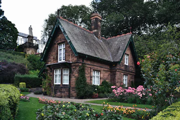 Maison en pierre au toit d'ardoise entourée d'un jardin fleuri